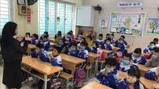 Hướng dẫn cho học sinh đeo khẩu trang và sử dụng dung dịch rửa tay khô khử khuẩn khi đến trường. Ảnh minh họa: Bích Huệ/TTXVN