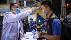 Một phóng viên thể thao được đo thân nhiệt trước khi vào sân tác nghiệp.