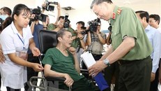 Đại tướng Tô Lâm thăm hỏi sức khỏe và trao quà tặng một đồng chí thương binh nặng đang điều dưỡng tại Trung tâm. (Ảnh: Đức Phương/TTXVN)