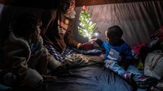 Gia đình anh Aguilar Duarte đến từ Honduras chụp ảnh với cây thông Giáng sinh trong lều của họ tại một trạm trú ẩn tạm thời ở trung tâm thành phố Tijuana.