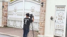 Một phóng viên đứng chờ săn tin trước cổng nhà bà Yingluck