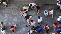 Nạn nhân vụ nổ nằm bất tỉnh ở sân chung cư. Cảnh sát phong tỏa hiện trường khám nghiệm ngay sau đó. Ảnh: H.L.