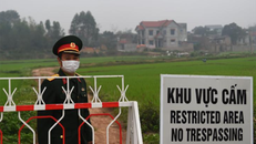 Một sĩ quan quân đội Việt Nam đứng gác cạnh biển cảnh báo khu vực phong tỏa xã Sơn Lôi, tỉnh Vĩnh Phúc, hôm 20/2. Ảnh: AFP.