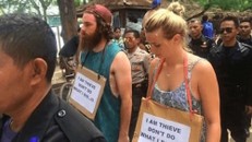 Cặp đôi phải diễu hành trong sự xấu hổ với tấm biển ghi dòng chữ: “Tôi là kẻ ăn cắp. Xin đừng làm như tôi”. Ảnh: SCMP.