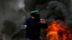 Người dân Palestine ném đá về phía binh sĩ Israel trong cuộc đụng độ biểu tình gần TP Ramallah ở Bờ Tây ngày 19-12, phản đối quyết định của Tổng thống Mỹ Donald Trump công nhận Jerusalem là thủ đô của Israel. Ảnh: REUTERS