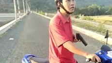 Ông Mai Thanh Tuấn dùng một vật giống khẩu súng đe dọa người dân. Ảnh cắt từ clip.