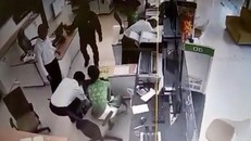 Nghi phạm mặc áo đen cầm vật giống khẩu súng khống chế nhân viên, yêu cầu đưa tiền. Ảnh cắt từ clip