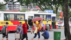 Một gia đình khẩn trương chạy vào bến xe khi trời mưa to. 