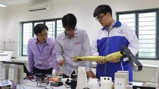 Hai nam sinh Phạm Đức Linh và Nguyễn Văn An cùng nhau nghiên cứu sản phẩm Cánh tay robot cho người khuyết tật liệt cơ tay toàn phần. Ảnh: TTXVN