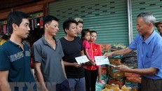 Chủ tịch Hội người Việt Nam tại tỉnh Attapeu Võ Văn Mừng trao tặng số tiền 1 triệu Kip cho 3 gia đình bị ảnh hưởng sau sự cố vỡ đập thủy điện. (Ảnh: Quang Thái/TTXVN)