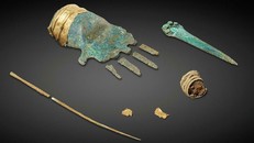 Bàn tay kim loại thời đồ đồng này đeo một chiếc vòng vàng. Bên cạnh đó là một con dao găm, một cái ghim bằng đồng và một vật cài tóc xoắn ốc. Hai vảy vàng thu được có thể là bong ra từ vòng đeo tay. (Ảnh: Philippe Joner/Cơ quan khảo cổ bang Bern).