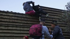 Những người di cư nhau vượt qua bức tường biên giới Mỹ từ Mexico. Ảnh: AP