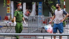 Công an hướng dẫn người dân đưa đồ tiếp tế cho người thân trong Bệnh viện hữu nghị Việt Đức qua cổng đường Tràng Thi. (Ảnh: Hoàng Hiếu/TTXVN)