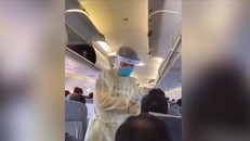 Nhân viên y tế đo nhiệt độ hành khách trước khi rời máy bay