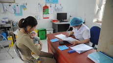 Nhân viên y tế khám sàng lọc, kiểm tra tình trạng của trẻ trước khi tiêm vaccine. Ảnh: Vũ Quang/TTXVN.