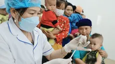 Người dân đưa trẻ đến tiêm chủng. Ảnh: Minh Quyết/TTXVN