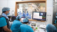 Các bác sĩ điều khiển robot từ bên ngoài để can thiệp mạch vành cho bệnh nhân bên trong phòng can thiệp.