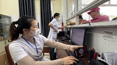 Nhân viên y tế quét mã lấy số và đăng ký khám bệnh tại các ki-ốt phát số tự động. Ảnh: Đinh Hương/TTXVN.