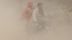 Một gia đình lái xe trong bụi mù dày đặc ở New Delhi