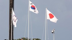 Cờ của 'Đài Bắc Trung Hoa' (Đài Loan), bên trái, tại Lễ trao huy chương cho nội dung bắn cung nam ở Trường bắn cung Công viên Yumenoshima, Tokyo, hôm thứ Hai. Lá cờ có hình một mặt trời nhỏ màu trắng đặt trên một vòng tròn màu xanh lam - một biểu tượng được lấy từ quốc kỳ Đài Loan - và năm vòng tròn Olympic, được bao quanh bởi một bông hoa mận châu Á màu xanh, trên nền trắng. (Ảnh: Yonhap)