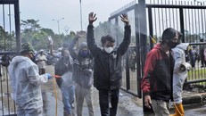 Binh sĩ Indonesia xịt khử trùng lên người dân đến sân vận động tại Tây Java để tiêm vaccine COVID-19. Ảnh: AP