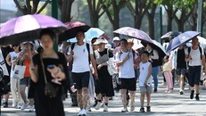 Người dân che ô tránh nắng khi di chuyển trên phố ở Bắc Kinh, Trung Quốc ngày 24/6/2023. Ảnh: AFP/TTXVN