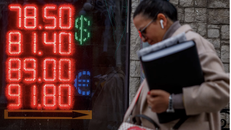 Người phụ nữ đi qua bảng điện tử hiển thị tỷ giá USD và euro so với đồng rúp Nga vào ngày 22/2/2022 tại Moskva. Ảnh: AFP/ Getty Images.