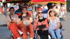 Du khách quốc tế trên xe xích lô đi tham quan phố cổ, Hồ Hoàn Kiếm. Ảnh: Thanh Tùng/TTXVN