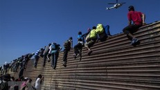 Người di cư vượt qua bức tường biên giới Mỹ-Mexico ở gần cửa khẩu El Chaparral, Tijuana, bang Baja California, Mexico ngày 25/11/2018. (Nguồn: AFP/TTXVN)