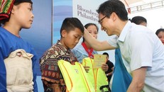 Phó Thủ tướng Chính phủ Vũ Đức Đam tặng áo phao cho các em nhỏ tại buổi lễ. Ảnh: Thanh Tùng/TTXVN