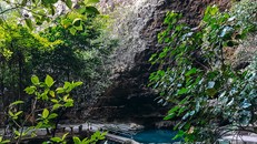 Một lòng hồ tự nhiên nước xanh trong vắt thấp thoáng sau những tán cây xanh đang nằm im lìm trong lòng hang