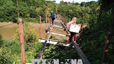 Người dân xã Tam Chung bất chấp tính mạng đi qua cầu để sang sông. (Ảnh: TTXVN) 