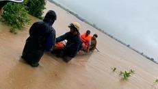 Lực lượng chức năng đưa người dân bị mắc kẹt vào bờ an toàn. (Nguồn: sggp.org.vn)