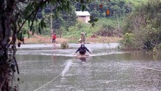 Người dân “chế” bè qua sông sau khi con đường ngang suối bị xóa sổ. (Ảnh: Hưng Thịnh/TTXVN) 