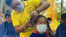 Anh Ngô Trọng Giáp cắt tỉa, căn chỉnh cẩn thận từng mái tóc cho bệnh nhân đang điều trị tại Bệnh viện Đa khoa huyện Triệu Phong. (Ảnh: TTXVN phát) 