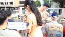 Cảnh sát giao thông phát tờ rơi tuyên truyền song ngữ cho khách du lịch trên xe buýt 2 tầng - Ảnh: VGP