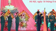 Chủ tịch nước Võ Văn Thưởng gắn Huân chương Chiến công hạng Nhất lên lá cờ truyền thống của Tổng Cục II, Bộ Quốc phòng. Ảnh: Thống Nhất/TTXVN