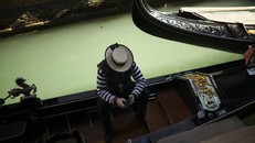 Một người trèo thuyền gondola ngồi đợi khách tại Venice. Ảnh: AP
