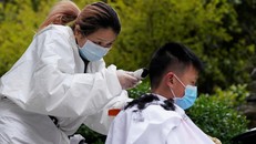 Xiong cẩn thận mặc một bộ đồ bảo hộ và găng tay và khử trùng kéo cùng tông đơ sau khi làm cho một khách hàng. Ảnh: Reuters