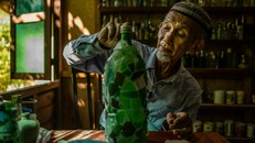 Người đàn ông sưu tầm chai lọ trên bãi biển