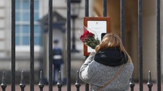 Một người phụ nữ đem theo hoa tới đặt trước cửa Cung điện Buckingham để tưởng nhớ Hoàng tế Philip. Ảnh: AP