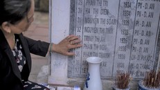 Bà Nguyễn Thị Thanh bên tấm bia khắc tên những nạn nhân của vụ thảm sát năm 1968. Ảnh: NY Times