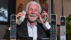 Kỹ sư Martin Cooper cầm trên tay chiếc điện thoại di động đầu tiên được sáng chế vào năm 1973 và mẫu iPhone mới nhất. Ảnh: AFP