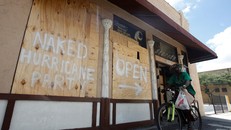 Người dân "trang trí" các tấm gỗ dùng để gia cố cửa bằng những thông điệp hài hước: "Tiệc đón bão khỏa thân mở cửa lối này". Ảnh: Reuters.