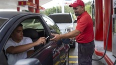 Nhân viên trạm xăng nhận thuốc lá từ một tài xế sau khi bơm xăng ở ngoại ô Caracas hôm 8/10 (Ảnh: AP).