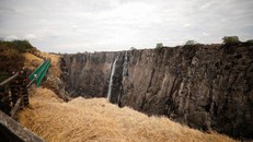 Du khách đi bộ qua cây cầu để chiêm ngưỡng "tia Victoria", nơi từng là thác nước hùng vĩ bậc nhất thế giới, hôm 5/12. (Ảnh: Reuters).