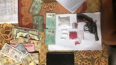 Tang vật súng ru-lô, ma túy, tiền, đô-la thu giữ từ đối tượng ma túy.