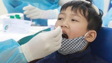 Học sinh trường Tiểu học Xuân Phương (Hà Nội) được nhân viên Trung tâm Y tế quận Nam Từ Liêm lấy dịch phết mũi và họng. Ảnh: Lê Phú.