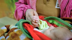 Bé H.T.P. ngủ yên trong vòng tay mẹ vào ngày tái khám