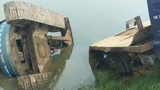 Máy xúc và xe tải lao xuống ao